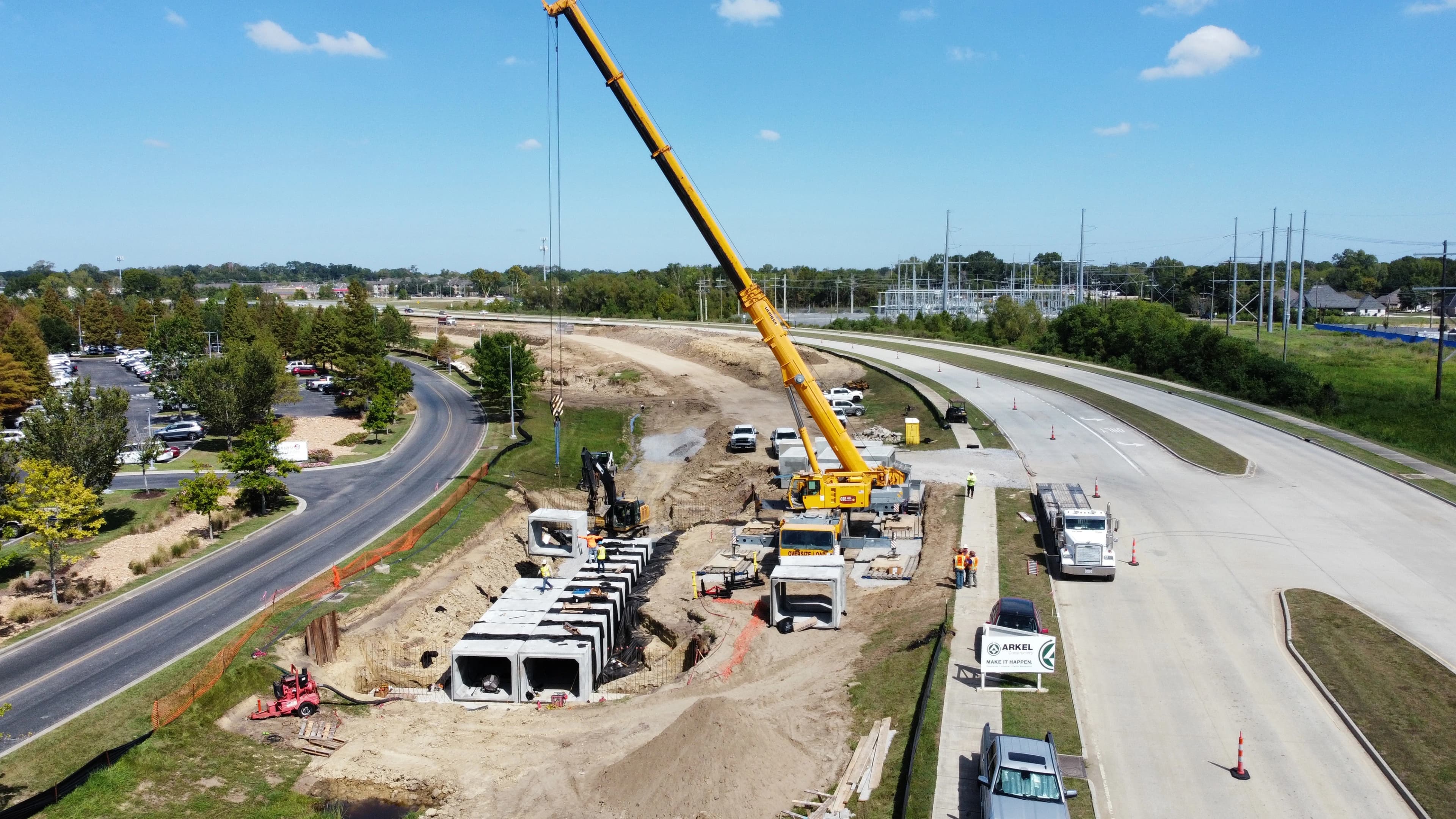 Cranes moving box culverts on in between interstate lanes on a sunny day