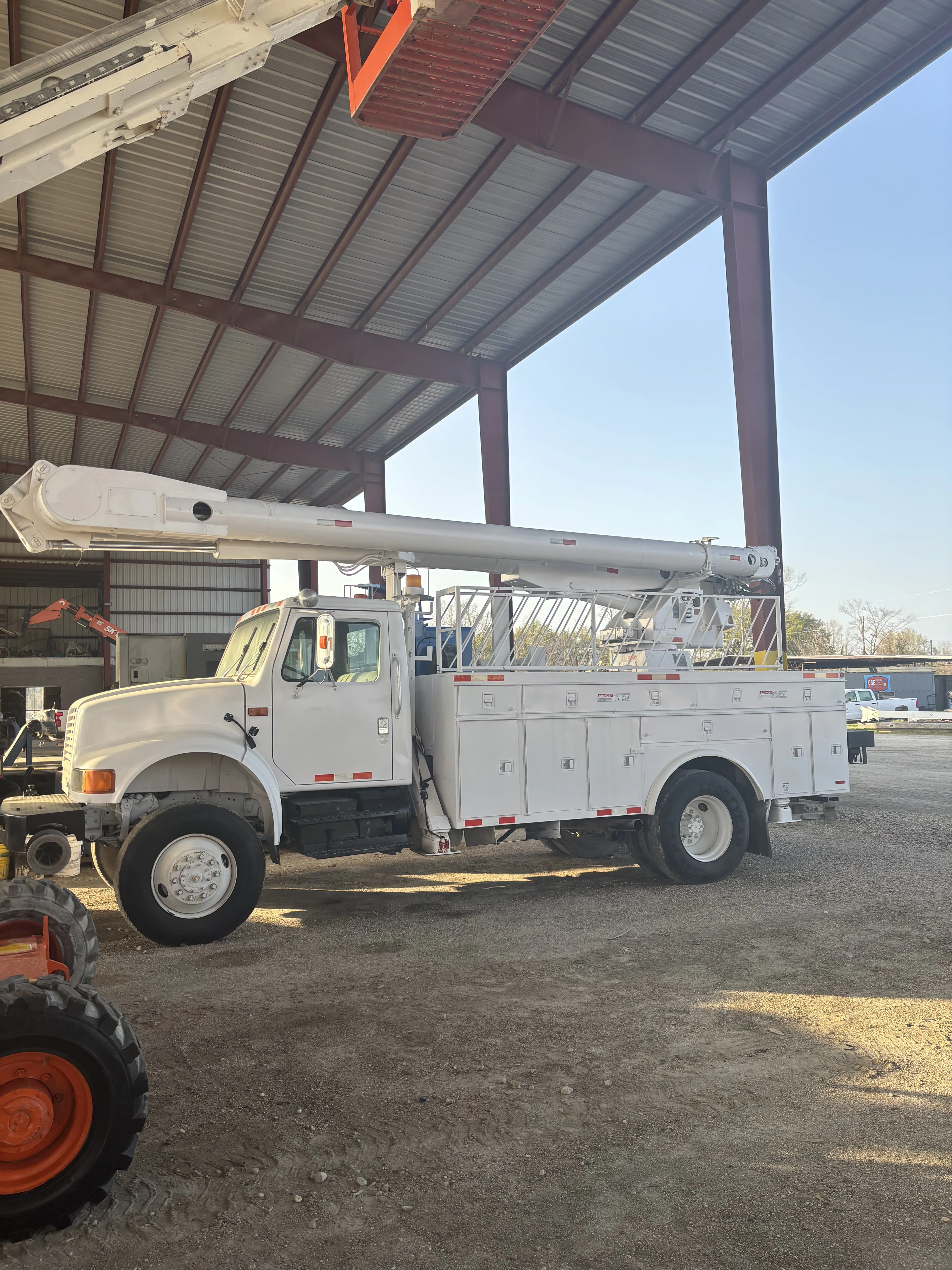 Boom Truck sitting on yard under metal roof