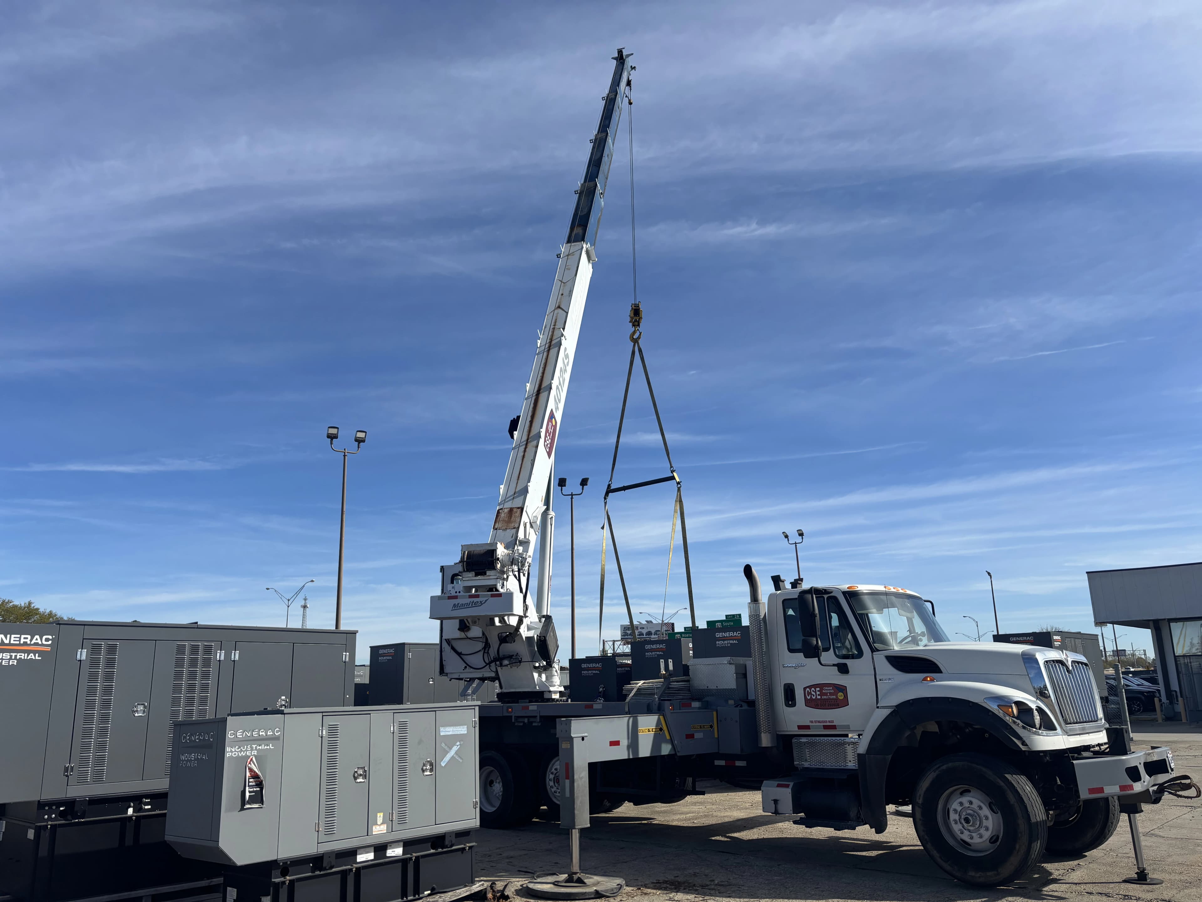 Large capitol companies crane truck moving a generac generator on a sunny day
