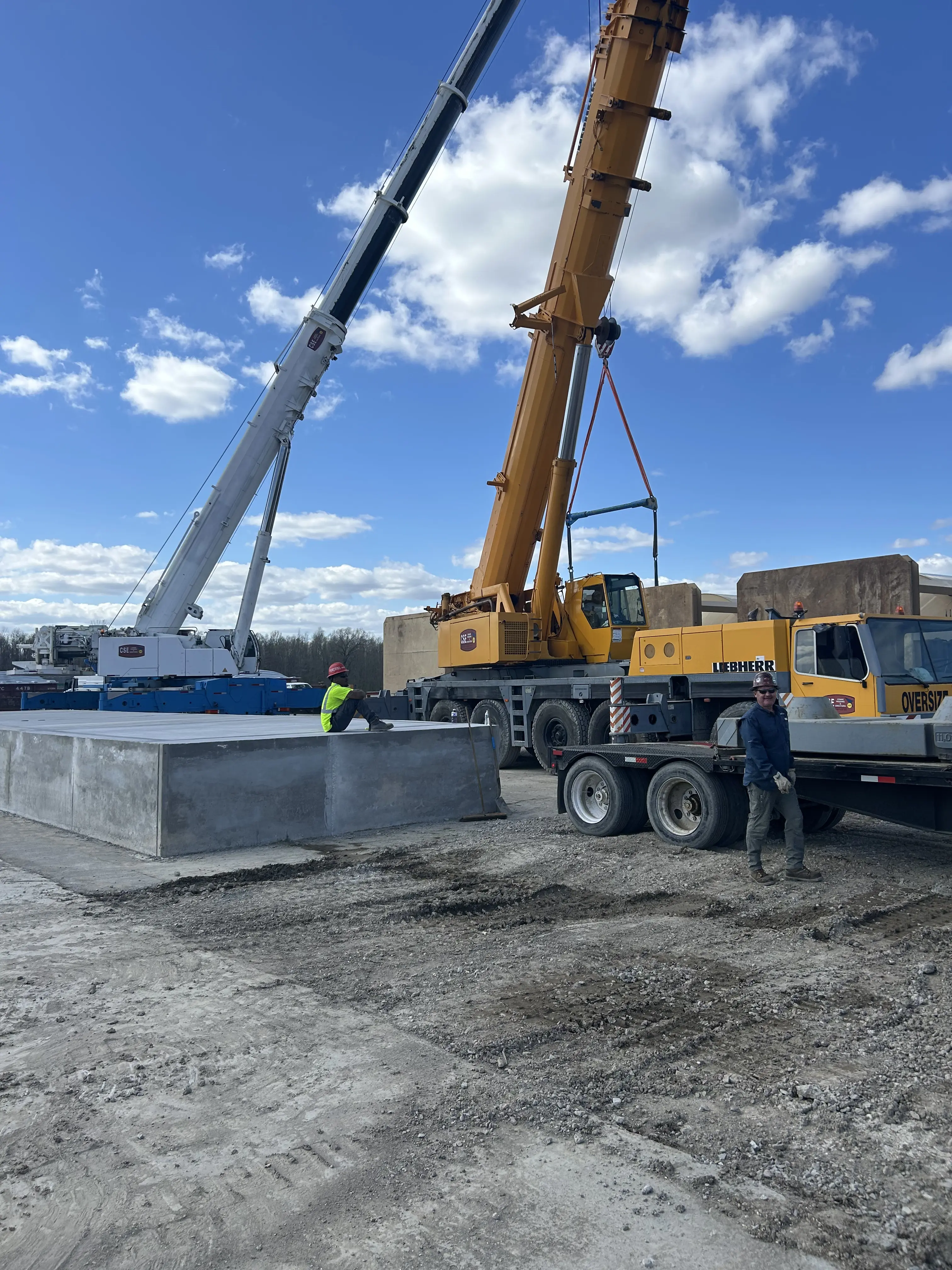 Two Cranes and two construction workers on a job site