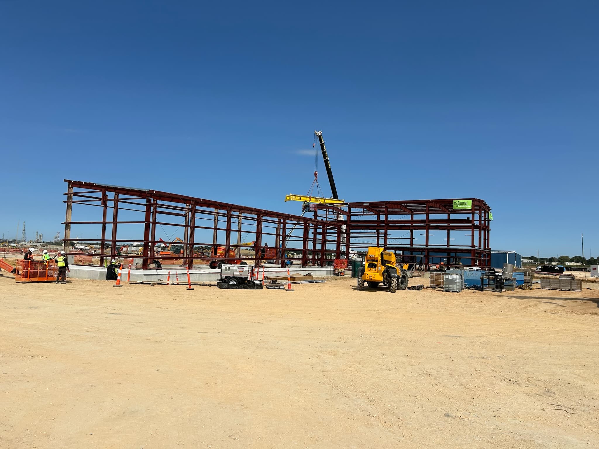 Crane moving large steel beam on job site on a sunny day